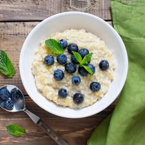 Glutenfreier Hirse-Porridge mit Banane, Heidelbeeren und Zimt in einer Schüssel als warmes Frühstück.